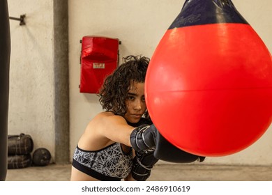 Hispanic young woman training boxing with red punching bags. - Powered by Shutterstock