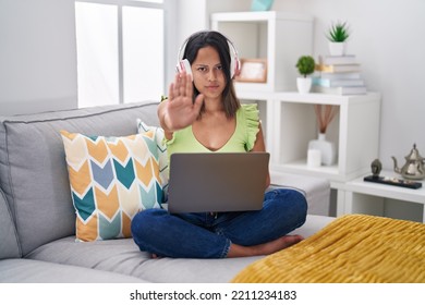 Hispanic Young Woman Using Laptop At Home Doing Stop Sing With Palm Of The Hand. Warning Expression With Negative And Serious Gesture On The Face. 