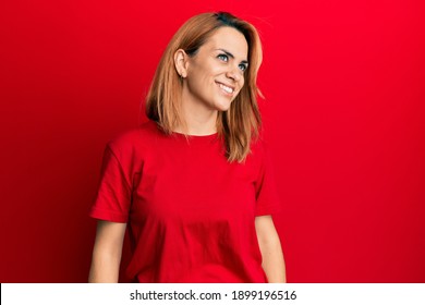 Hispanic Young Woman Wearing Casual Red T Shirt Looking Away To Side With Smile On Face, Natural Expression. Laughing Confident. 