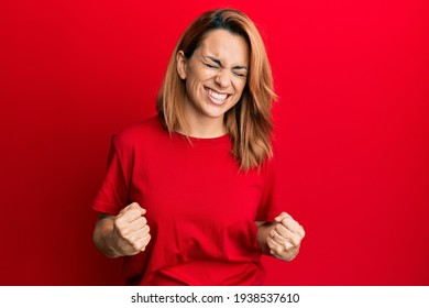 Hispanic Young Woman Wearing Casual Red T Shirt Very Happy And Excited Doing Winner Gesture With Arms Raised, Smiling And Screaming For Success. Celebration Concept. 