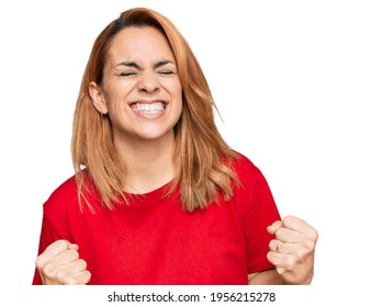 Hispanic Young Woman Wearing Casual Red T Shirt Very Happy And Excited Doing Winner Gesture With Arms Raised, Smiling And Screaming For Success. Celebration Concept. 