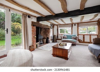 Historic 17th Century traditional furnished cottage living room with inglenook fireplace and exposed original timbers. - Shutterstock ID 2130961481