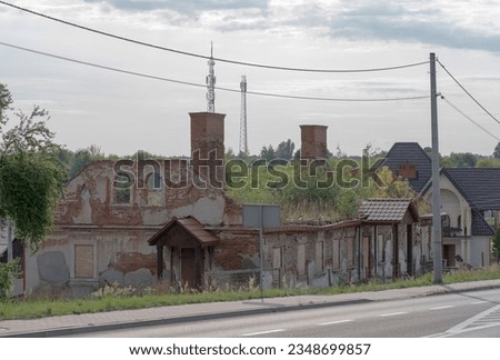 Historic Brick Building. A house in ruins without a roof against the background of a gray sky.Devastated red brick house. Visible brick chimneys and no windows or roof. Cell phone masts in the backgr.