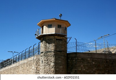 Historic brick prison wall showing guard tower and coiled barbed wire