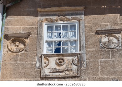 A historic building facade with a window adorned with intricate stone carvings and framed by ornate details - Powered by Shutterstock