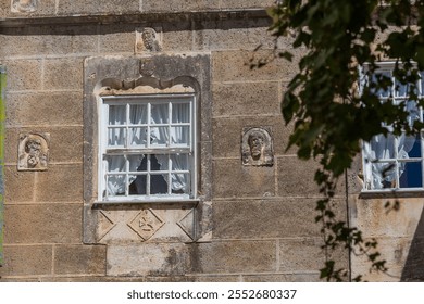 A historic building facade with a window adorned with intricate stone carvings and framed by ornate details - Powered by Shutterstock