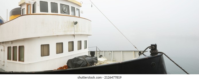 Historic Cargo Boat Moored To A Pier, In A Thick White Morning Fog, Close-up. Kiel, Germany. Transportation, Fishing, Sailing, Logistics, Industry, Traditional Craft, Past, History. Panoramic Image