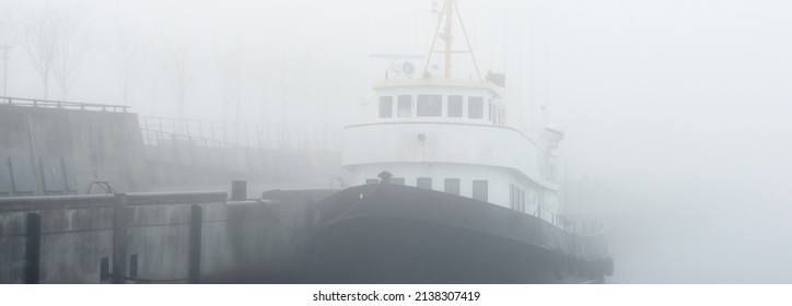 Historic Cargo Boat Moored To A Pier, In A Thick White Morning Fog, Close-up. Kiel, Germany. Transportation, Fishing, Sailing, Logistics, Industry, Traditional Craft, Past, History. Panoramic Image