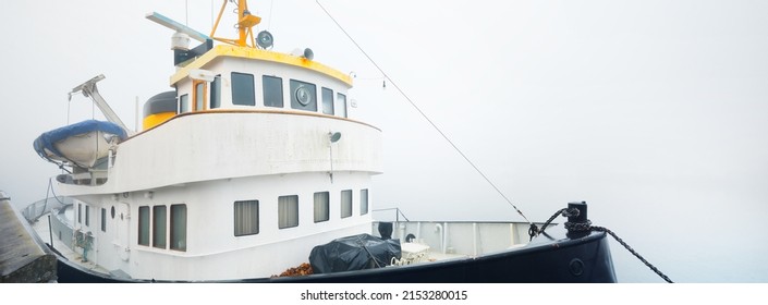 Historic Cargo Boat Moored To A Pier, In A Thick White Morning Fog, Close-up. Kiel, Germany. Transportation, Fishing, Sailing, Logistics, Industry, Traditional Craft, Past, History. Panoramic Image