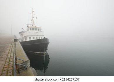 Historic Cargo Boat Moored To A Pier, In A Thick White Morning Fog, Close-up. Kiel, Germany. Transportation, Fishing, Sailing, Logistics, Industry, Traditional Craft, Past, History. Panoramic Image