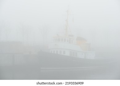 Historic Cargo Boat Moored To A Pier, In A Thick White Morning Fog, Close-up. Kiel, Germany. Transportation, Fishing, Sailing, Logistics, Industry, Traditional Craft, Past, History. Panoramic Image