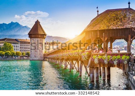 Historic city center of Lucerne with famous Chapel Bridge and Mount Pilatus summit in the background in golden evening light at sunset with blue sky and clouds, Canton of Lucerne, Switzerland
