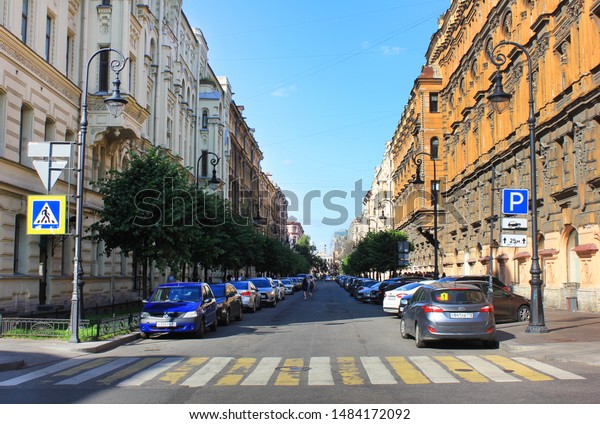 Historic city street with old decorative houses,\
crosswalk and cars parked near curb in Saint Petersburg, Russia on\
August 2019