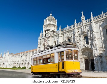 historic classic yellow tram of Lisbon built partially of wood in front of famous Jeronimos monastery, Portugal