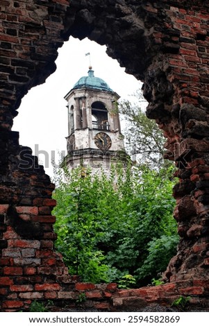 Historic Clock Tower Framed by Ruins and Greenery