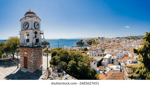 Historic clock tower overlooking the rooftops of Skiathos Town on the Greek island of Skiathos. This panoramic view captures whitewashed houses with terracotta roofs, the blue Aegean Sea 
