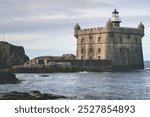 A historic coastal setting, dominated by a stone fort or tower with turrets