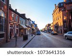 Historic, colonial Main Street in Annapolis, Maryland just after sunrise. The Historic District has more than 60 surviving colonial buildings. A view of red, cobblestone Main Street toward City Dock.