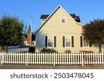 Historic colonial style house surrounded by a white picket fence taken at a residential community in a historical town