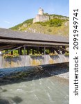 Historic covered bridge over the river Dranse and the Castle Bâtiaz in Martigny, Valais, Switzerland