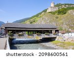 Historic covered bridge over the river Dranse and the Château de la Bâtiaz in Martigny, Valais, Switzerland