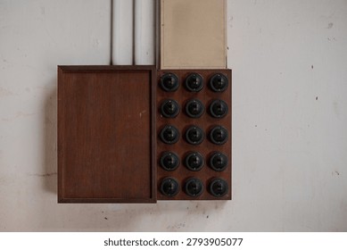 Historic electrical switchboard featuring multiple rotary switches mounted on a wooden control panel. Vintage electrical infrastructure preserved as part of industrial and technological heritage.