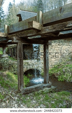 historic farm building with a wooden structure for water drainage. Water outlet to drive a water wheel. Old wooden city, energy, running water