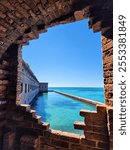 Historic Fort Jefferson viewed through a crumbled brick arch, framing vibrant turquoise waters of Dry Tortugas National Park.