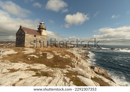 Historic lighthouse, ocean view, stone building double story, slate roof, a walkway around the light room gives the impression of a castle, sits on a rocky shore of the Atlantic ocean,