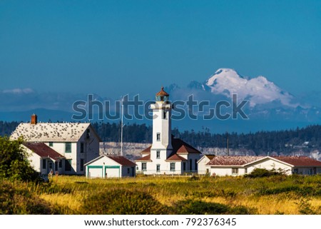 A historic lighthouse on the coast with a huge mountain in the background.  Stockfoto © 