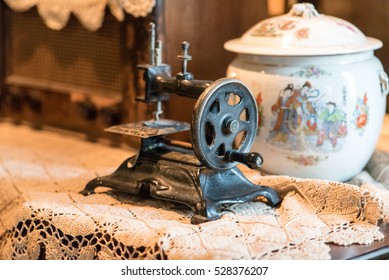 Historic manual sewing machine in Chinese museum, vase in background