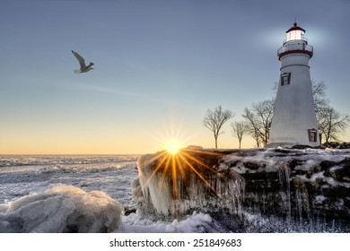 The historic Marblehead Lighthouse in Northwest Ohio sits along the rocky shores of the frozen Lake Erie. Seen here in winter with a colorful sunrise and snow and ice.