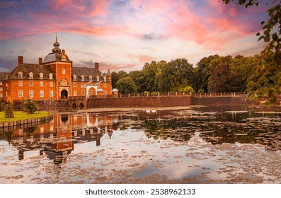 Historic moated castle Wasserburg Anholt in Isselburg, Germany, at sunset. Red brick architecture reflects on lily-covered water, surrounded by lush greenery, with two swans adding a fairytale ambianc - Powered by Shutterstock