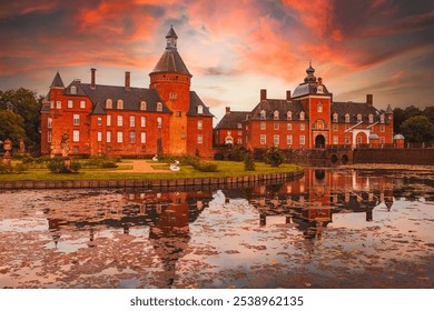 Historic moated castle Wasserburg Anholt in Isselburg, Germany, at sunset. Red brick architecture reflects on lily-covered water, surrounded by lush greenery, with two swans adding a fairytale ambianc - Powered by Shutterstock