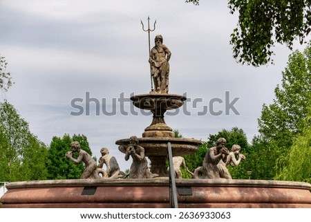 Historic Neptune fountain located in Odolanów, Greater Poland. The sculpture features the sea god Neptune with a trident on top, surrounded by figures playing conch shells at the lower level.