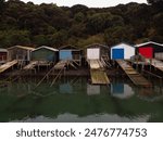 Historic old colorful boat sheds colored wooden houses on Duvauchelle Bay shore in Akaroa Harbour Banks Peninsula Canterbury South Island New Zealand