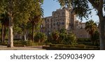 historic Palazzo dei Normanni in Palermo, Sicily, framed by lush gardens and palm trees, the architectural grandeur of Norman Palace amidst peaceful garden environment