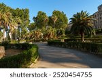 Historic Palazzo dei Normanni in Palermo, Sicily, framed by lush gardens and palm trees, the architectural grandeur of Norman Palace amidst peaceful garden environment