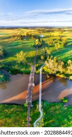 Historic railway bridge and pedestrian bridge across Macquarie river in Dubbo town of Australian Great Western Plains - aerial vertical panorama.