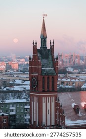 Historic red brick clock tower overlooking a snowy cityscape at sunrise