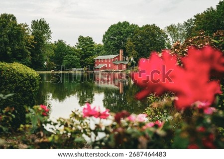 Historic Red Mill Reflected on Calm River Surrounded by Green Trees and Nature
