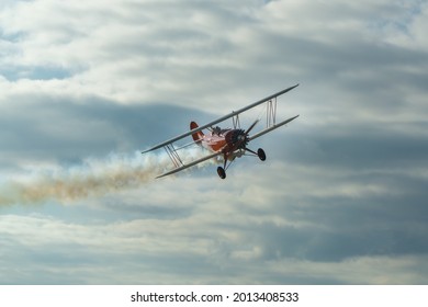 The historic red plane flies against the background of clumping clouds.