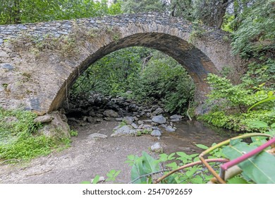 Historic stone bridge Pont du Bucatoghju in Corsica surrounded by lush greenery and natural beauty during daytime - Powered by Shutterstock