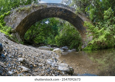 Historic stone bridge Pont du Bucatoghju in Corsica surrounded by lush greenery and natural beauty during daytime - Powered by Shutterstock