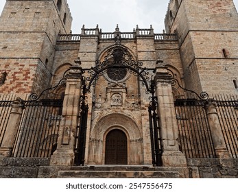 Historic stone cathedral entrance with ornate iron gate, showcasing medieval architecture. - Powered by Shutterstock