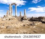 Historic stone columns rising against a clear blue sky, presenting an ancient architectural marvel set amidst stunning natural surroundings.