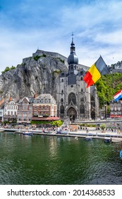 Die historische Stadt Dinant mit der belgischen Flagge und der Zitadelle auf dem Felsen und der Collegiate Church Notre-Dame am Fluss Meuse, Wallonien, Belgien