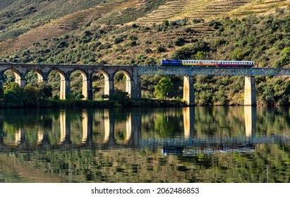 Historic Train On A Bridge Of The Douro Line In The Middle Of The Port Wine Vineyards