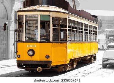 Historic tram or streetcar in the city centre of Milan in Italy. Single old timer car for public transport passing the cathedral and opera in midtown. Blurred black and white vintage background. 