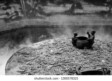 Historic Well With Ancient Chinese Currency And Bronze Character Statues In Chinese Temple